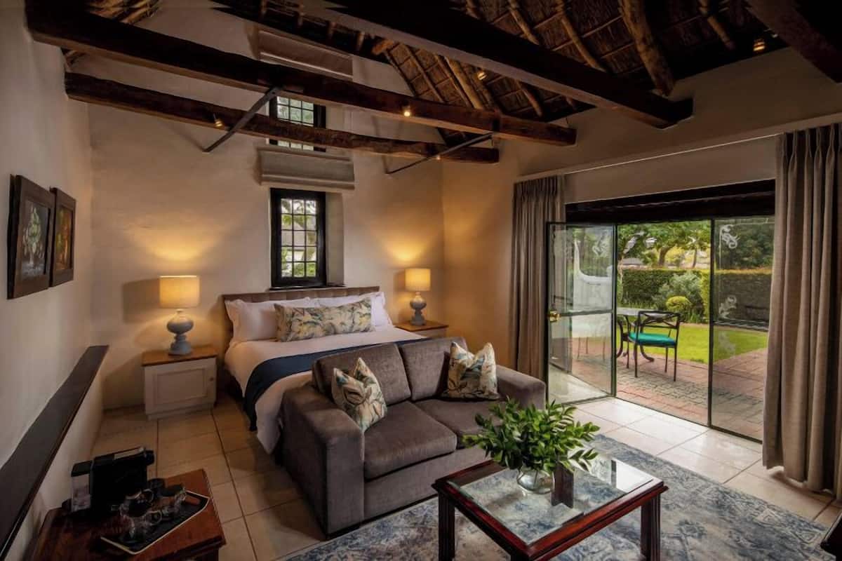 Une chambre d’hôtel avec un lit, un canapé, une table basse, une fenêtre et une vue sur le jardin.