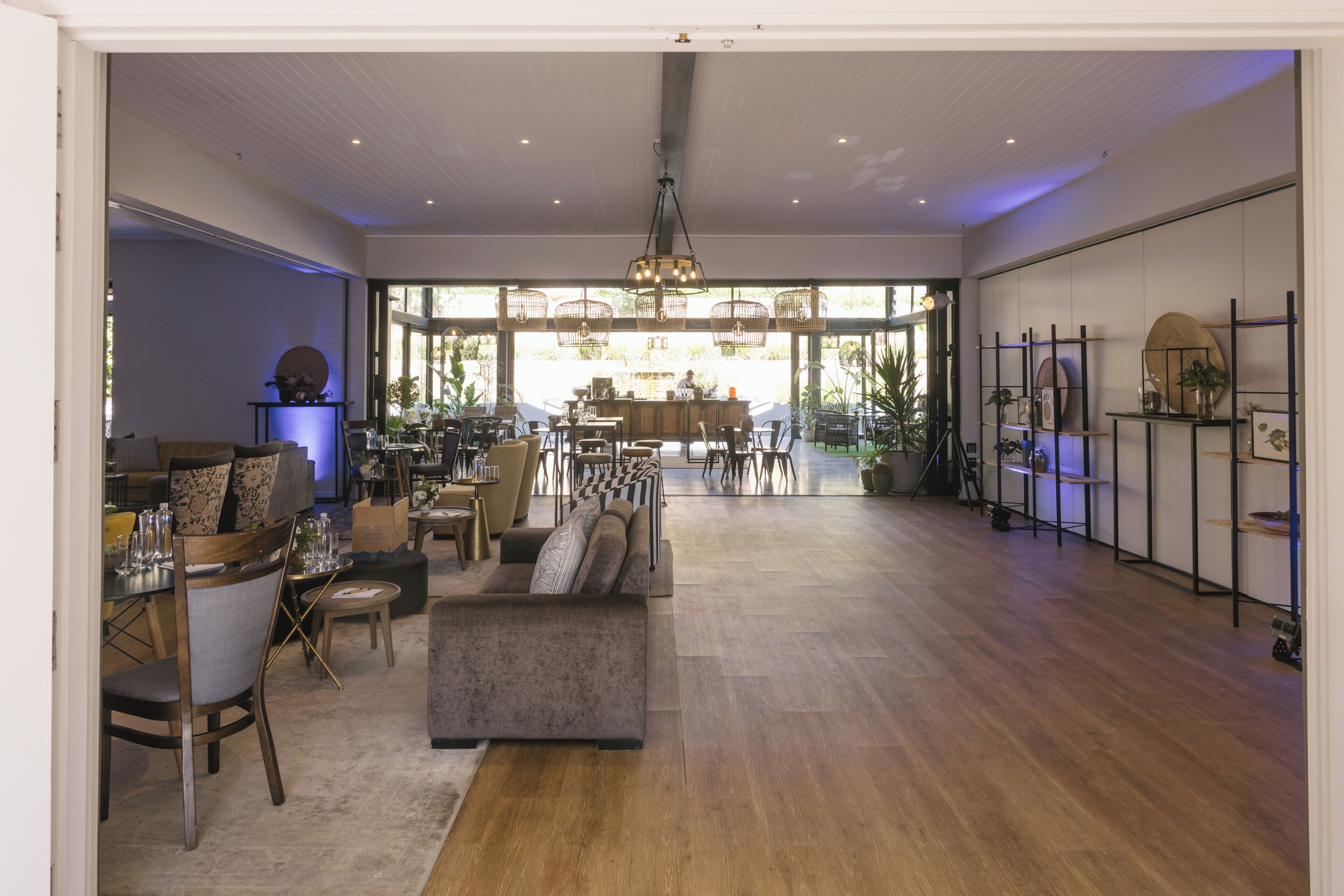 A spacious, well-lit interior with a central seating area, multiple tables, and a bar.