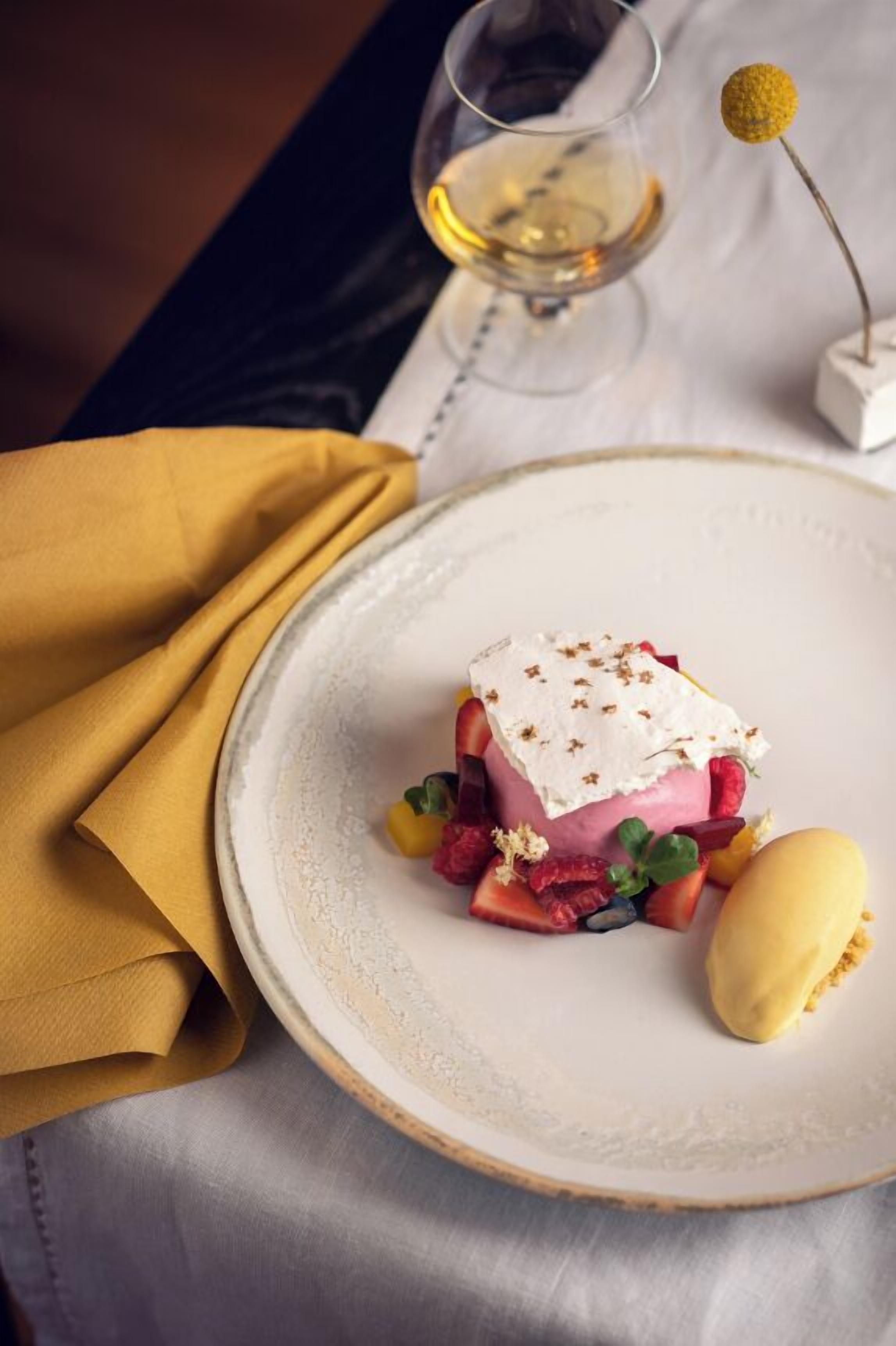 A dessert on a plate with a glass of white wine and a yellow napkin.