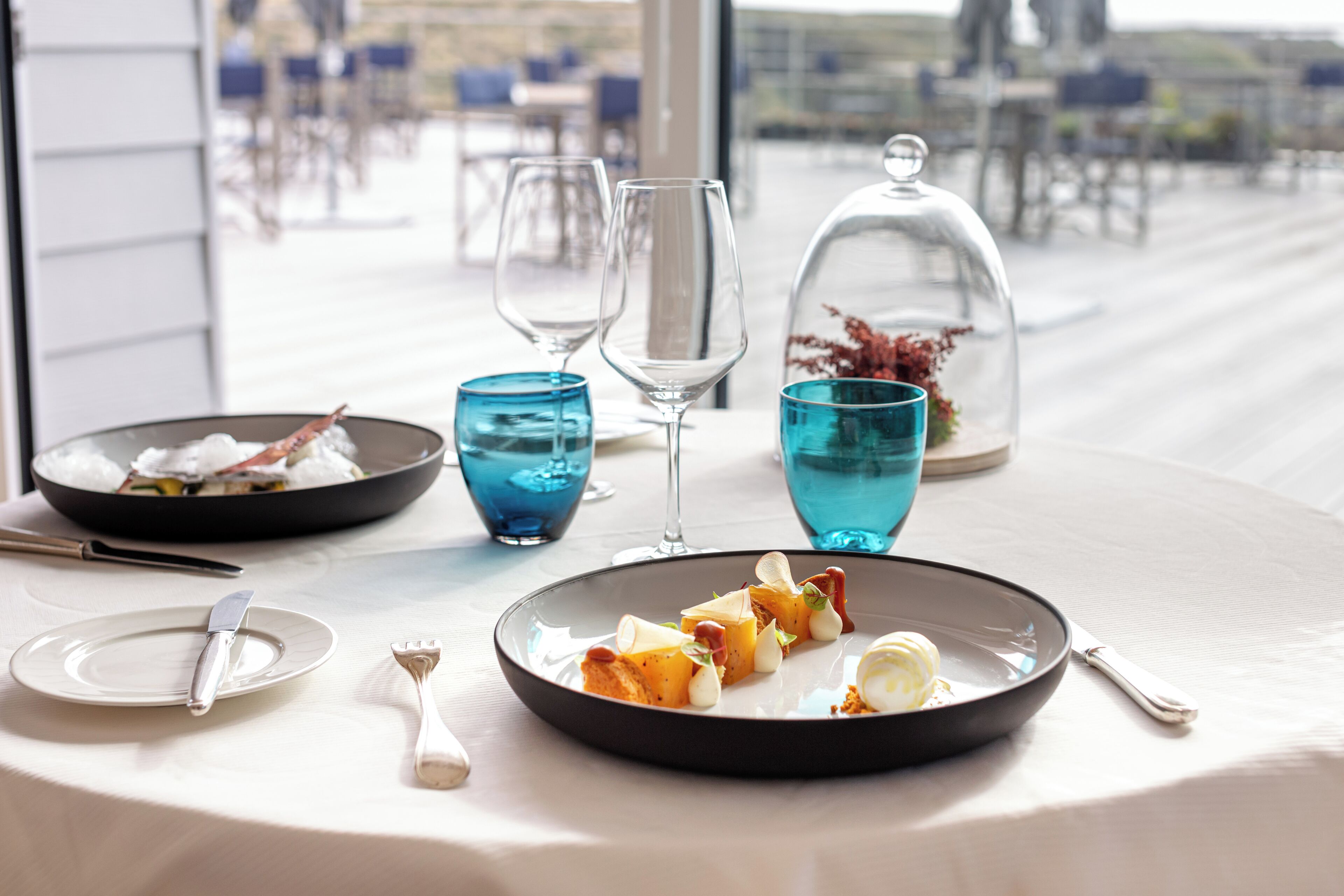 Een eettafel gedekt met een bord eten, een glas water en een wijnglas.
