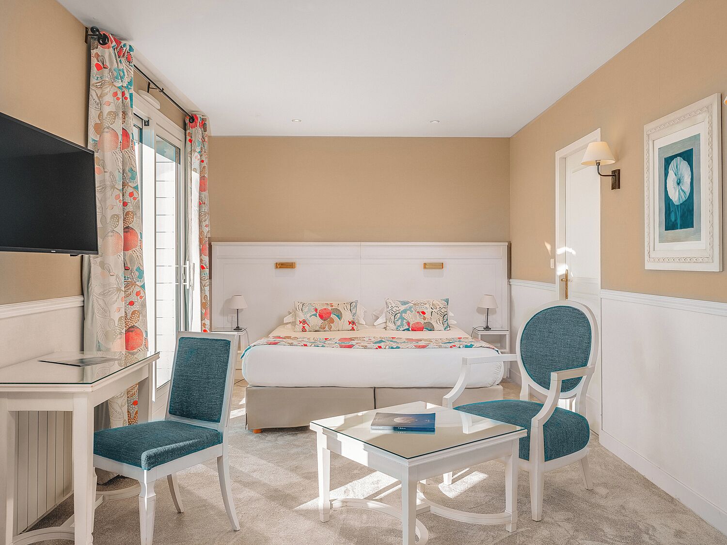 A hotel room with a bed, two chairs, a TV, and a small table.