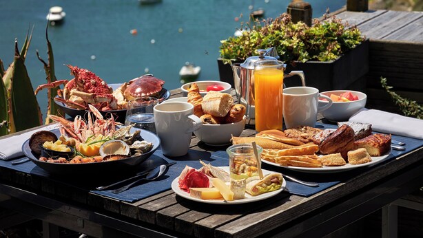 A table with breakfast items and a scenic view of the sea with boats. - Castel Clara Thalasso & Spa (Bangor)