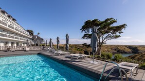 A swimming pool with lounge chairs and umbrellas, overlooking a scenic landscape with a building in the background. - Castel Clara Thalasso & Spa (Bangor)