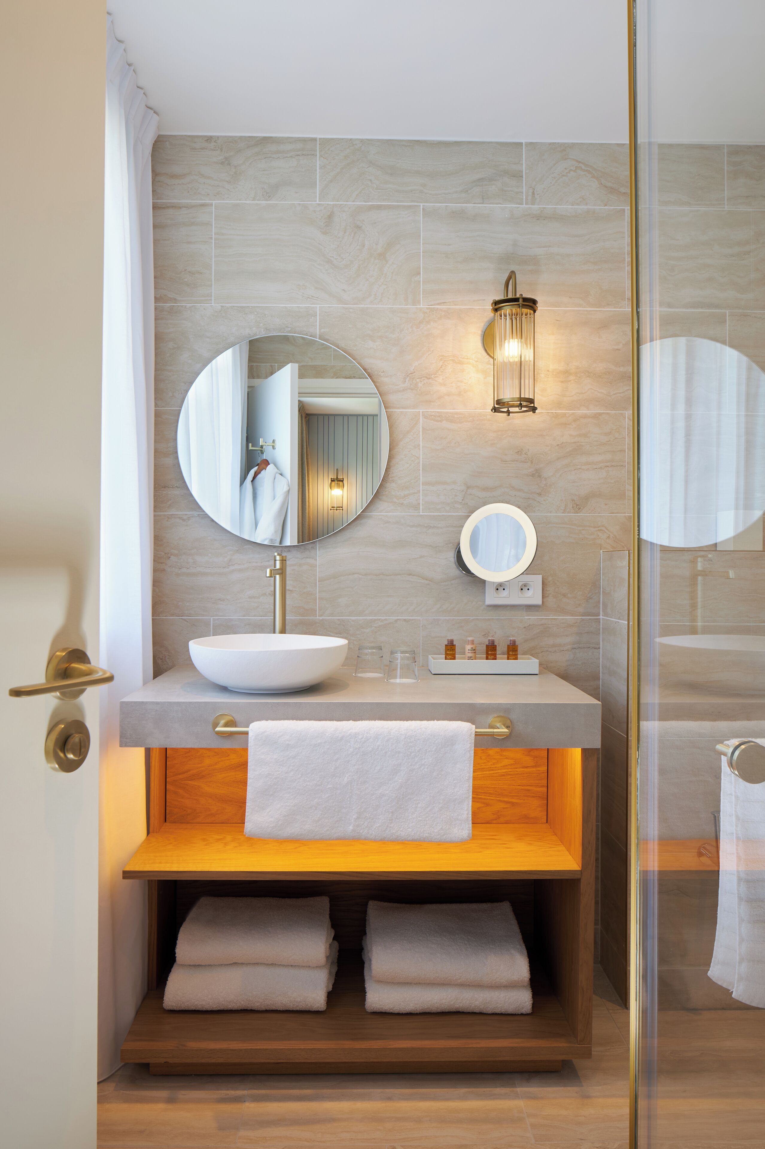 Un baño moderno con un espejo grande, un lavabo sobre encimera y un mueble de tocador de madera.