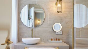 Un baño moderno con un espejo grande, un lavabo sobre encimera y un mueble de tocador de madera.