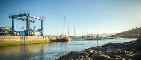 A harbor with boats, a crane, and rocky shores.