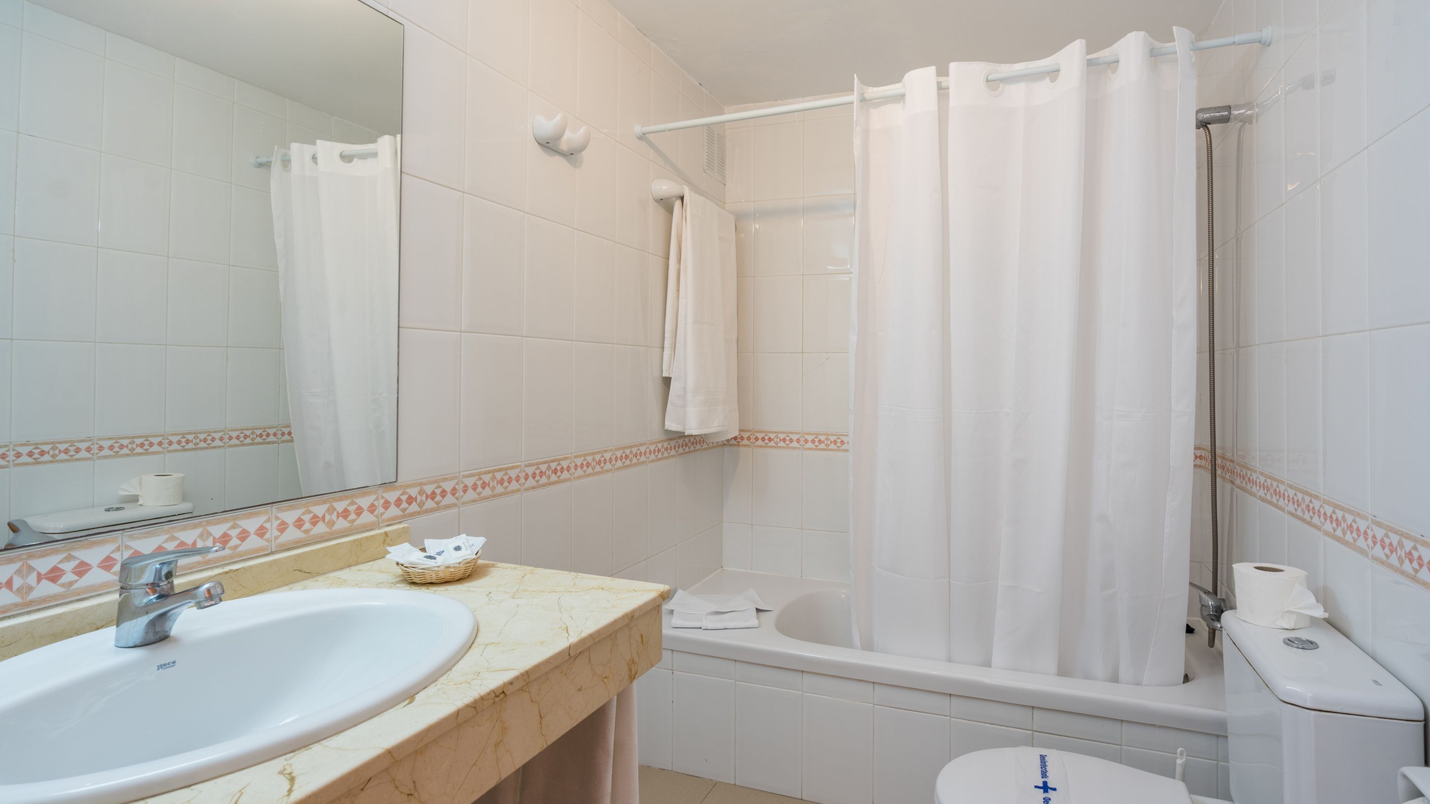 Un baño con lavabo, espejo, ducha e inodoro.