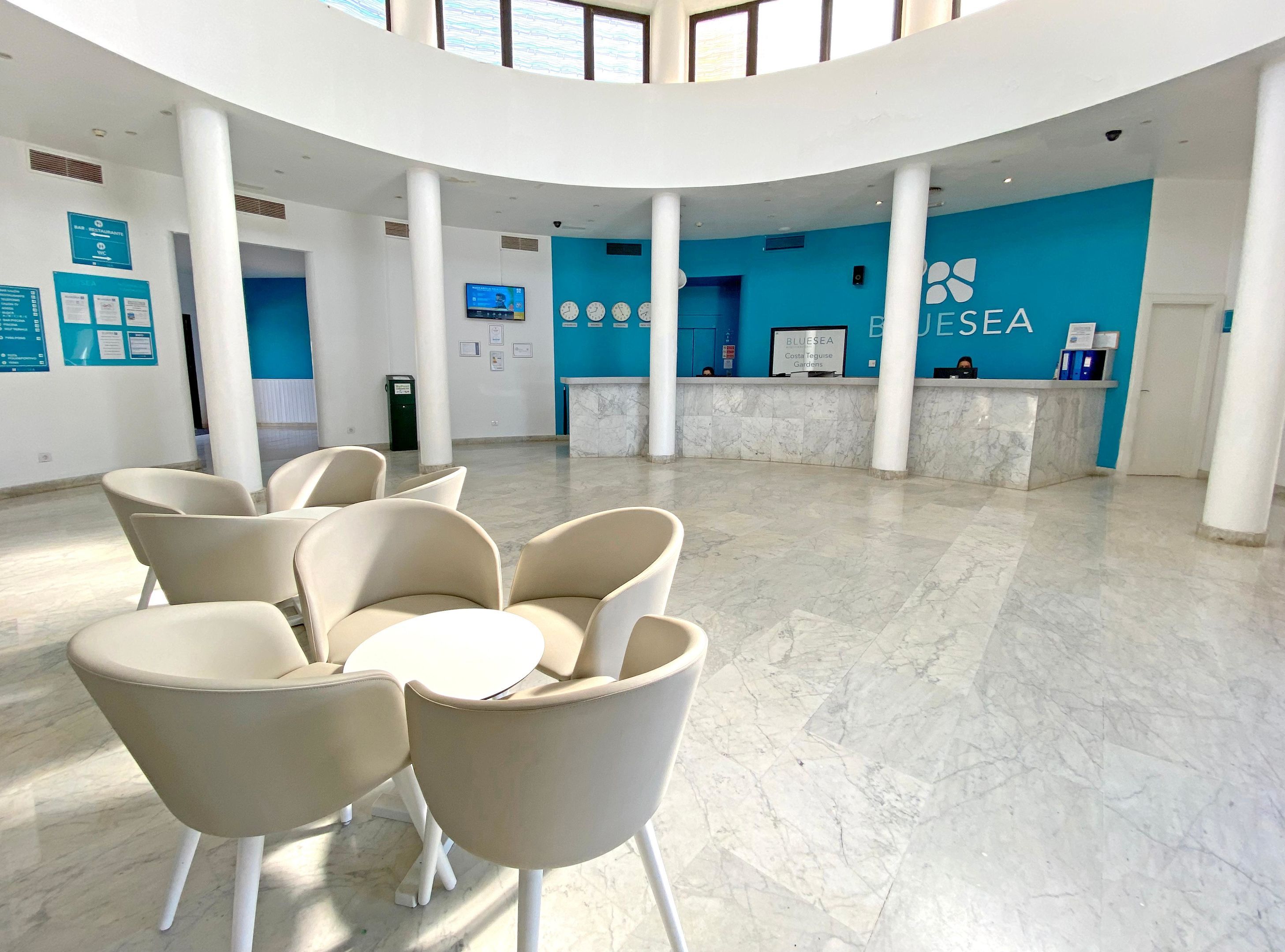 A spacious lobby with a reception desk, seating area, and a high ceiling with natural light.
