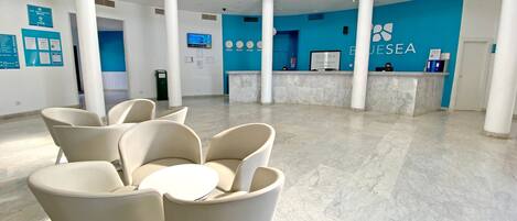 A spacious lobby with a reception desk, seating area, and a high ceiling with natural light.