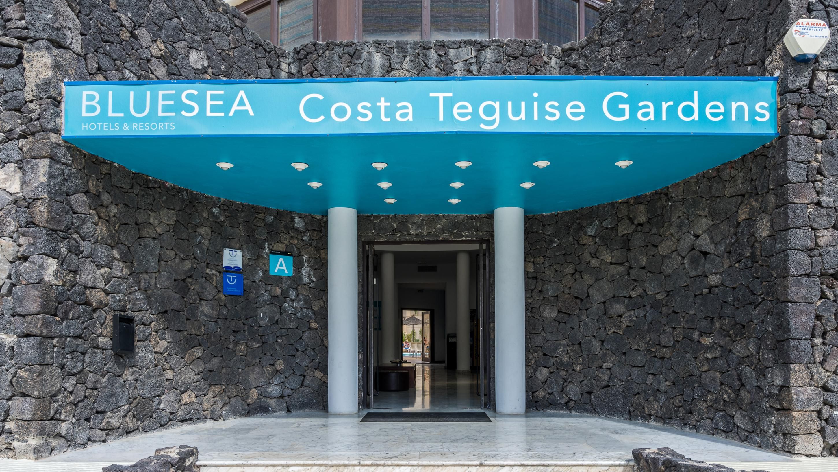 La entrada a BlueSea Costa Teguise Gardens, con fachada de piedra y un letrero sobre la entrada.