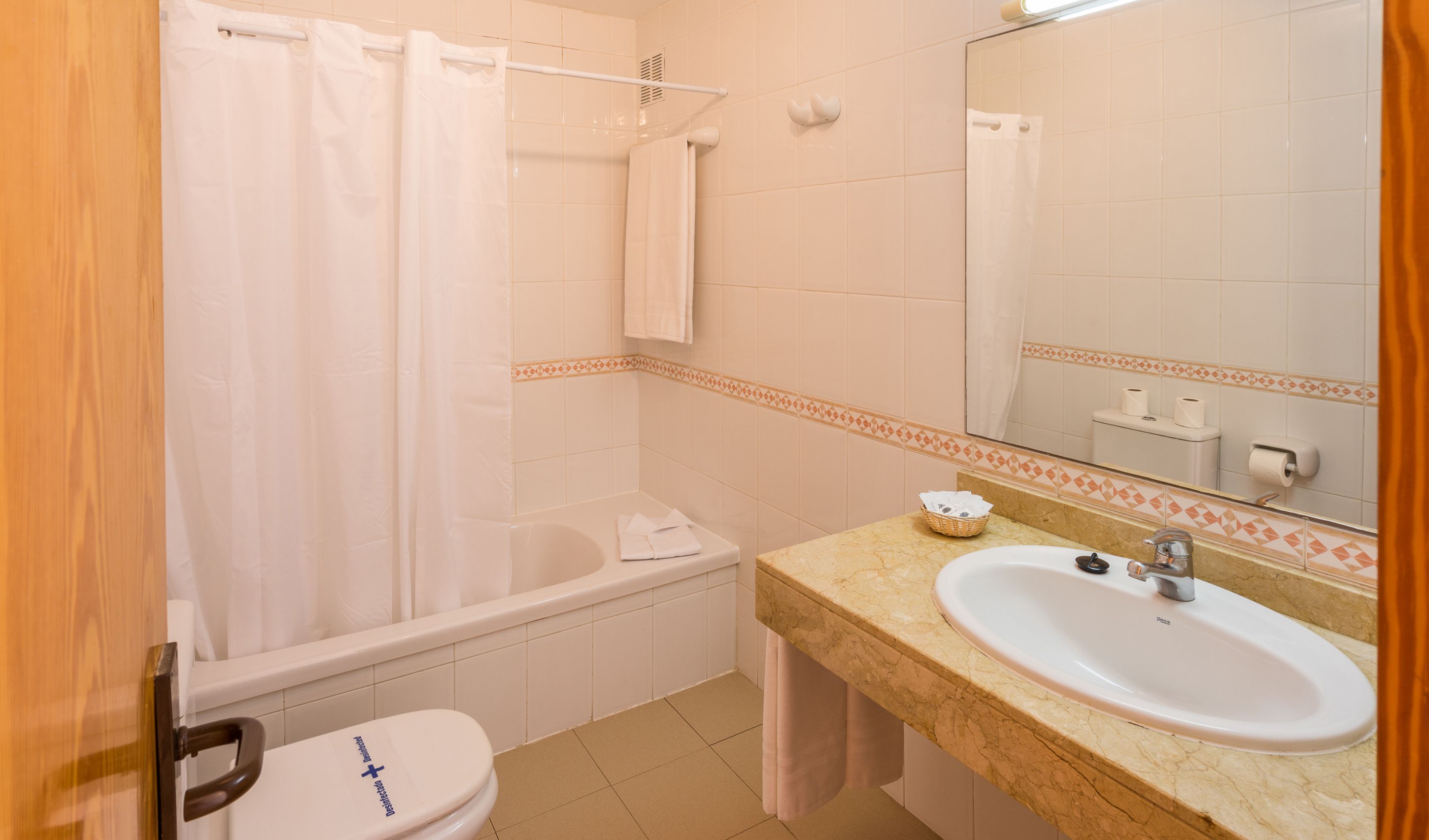 A bathroom with a bathtub, toilet, sink, and a mirror.