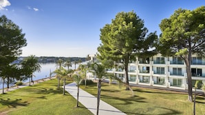 A modern building with multiple balconies overlooking a body of water. - Hotel BelleVue Club (Alcúdia)