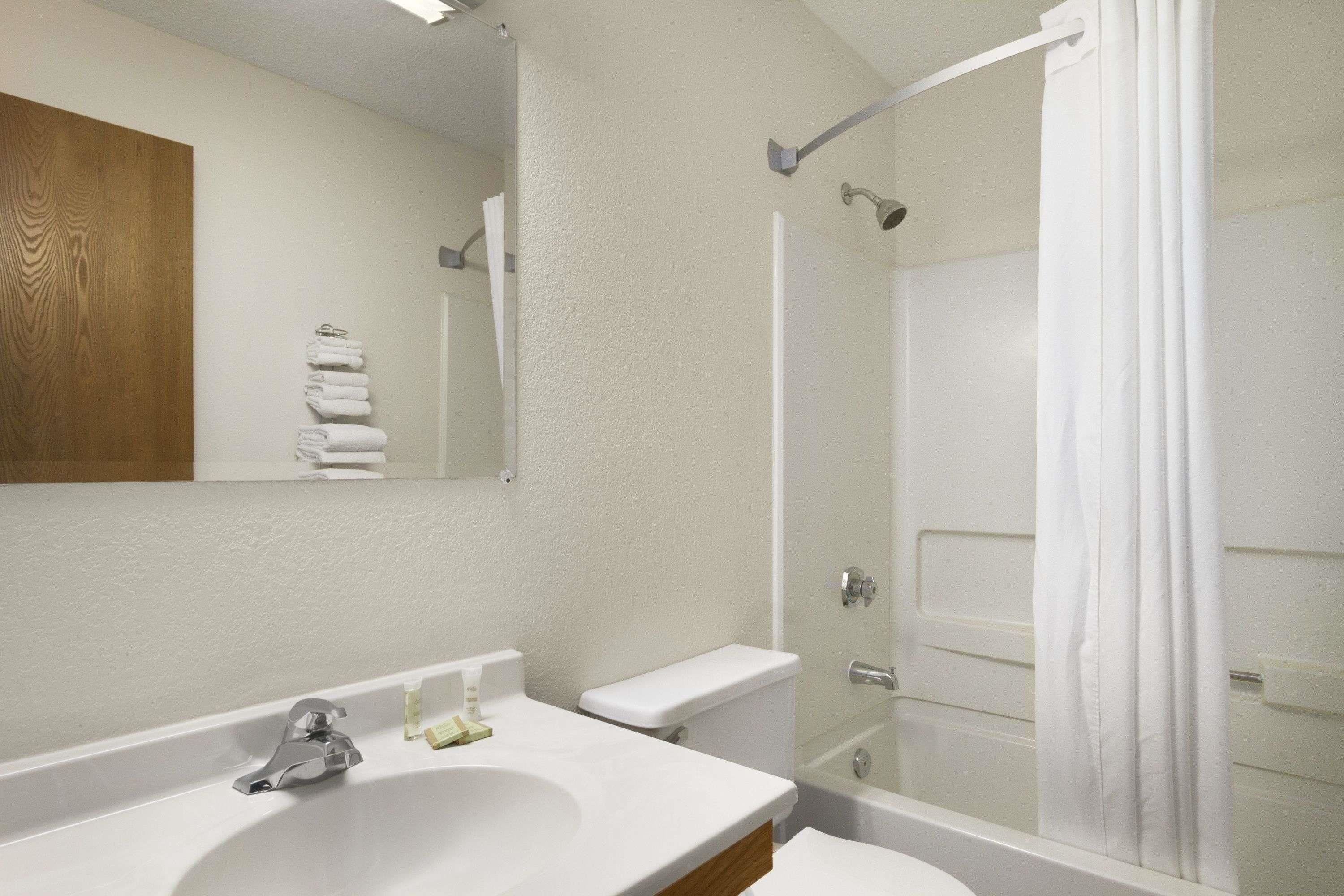 A modern bathroom with a white sink, mirror, and toilet.