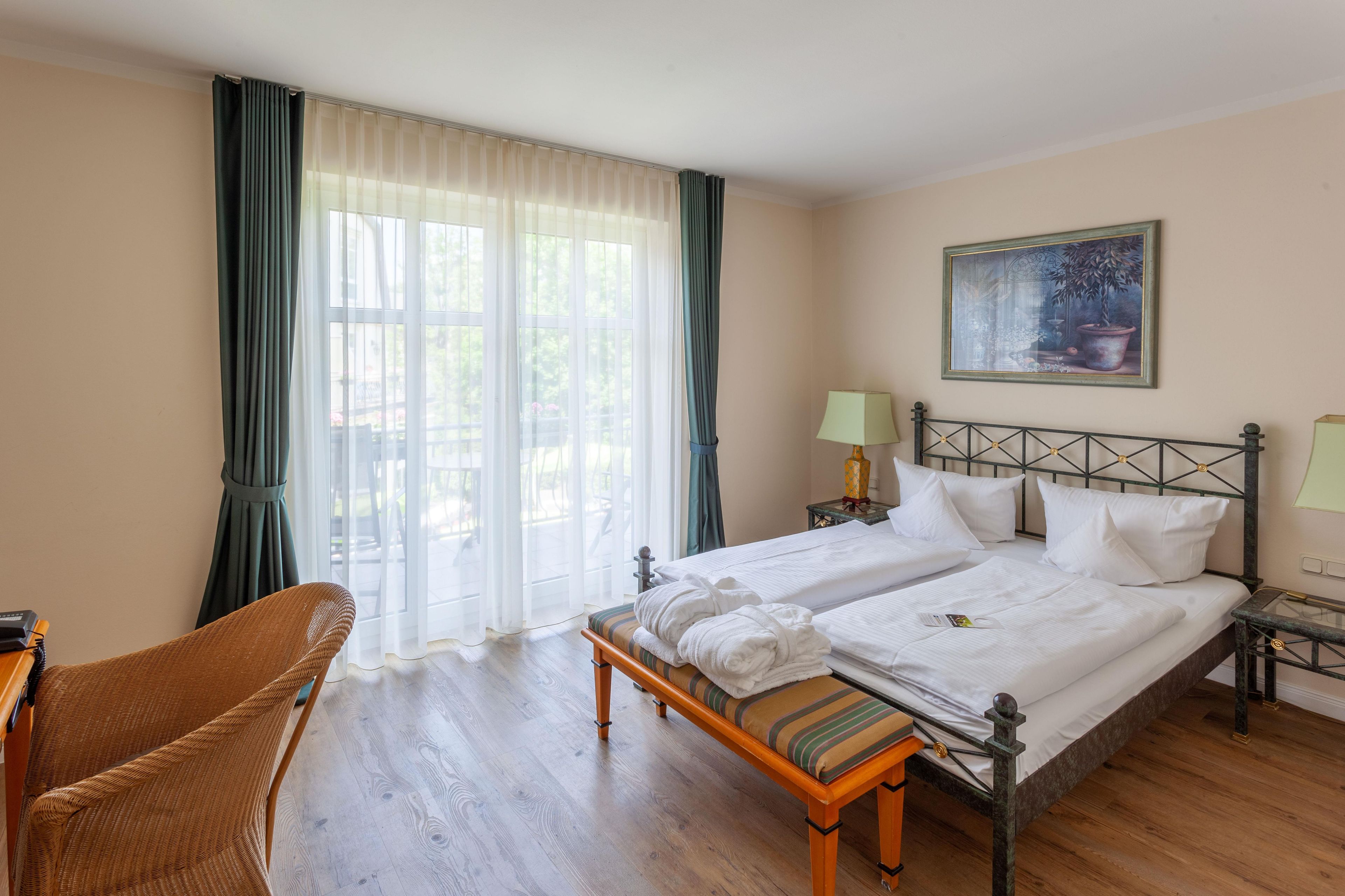 Ein Doppelbett mit weißen Bettwäsche, ein Nachttisch mit Lampe, ein Sessel und ein Gemälde an der Wand.