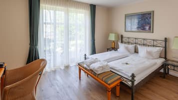 Ein Doppelbett mit weißen Bettwäsche, ein Nachttisch mit Lampe, ein Sessel und ein Gemälde an der Wand.