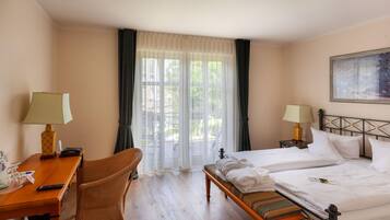 Una habitación de hotel con cama, dos mesitas de noche, un escritorio, una silla y una ventana con cortinas.