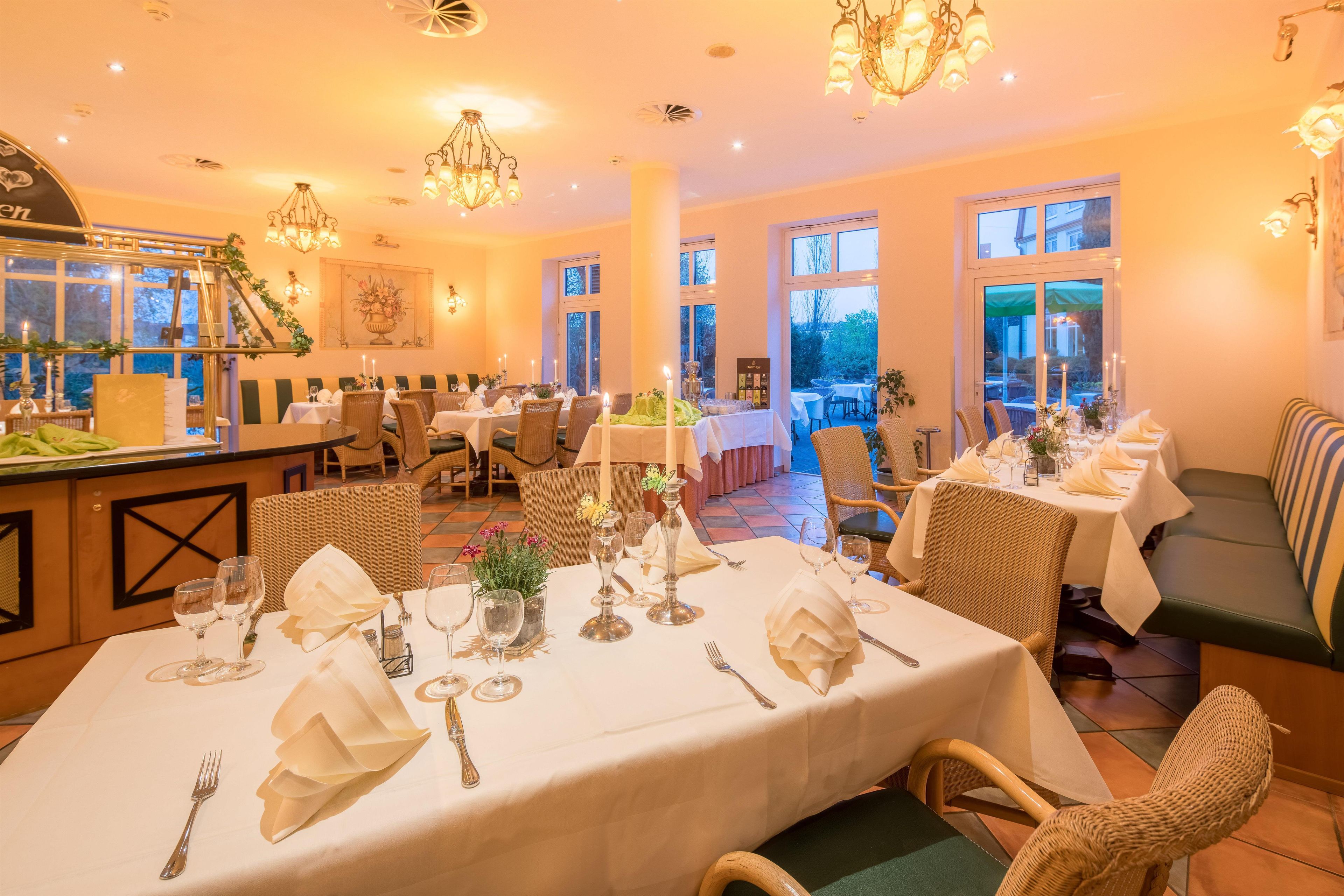 Ein Restaurant mit mehreren gedeckten Tischen für Gäste, ausgestattet mit weißen Tischdecken und edlem Geschirr.