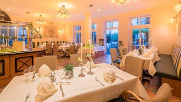 Ein Restaurant mit mehreren gedeckten Tischen für Gäste, ausgestattet mit weißen Tischdecken und edlem Geschirr.