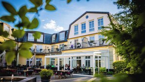 Une cour dotée d’un espace extérieur aménagé avec des sièges, d’une fontaine et d’un bâtiment comportant de nombreux balcons et de grandes fenêtres.