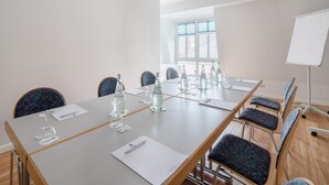 Een vergaderzaal met een lange tafel, stoelen, waterflesjes en documenten.