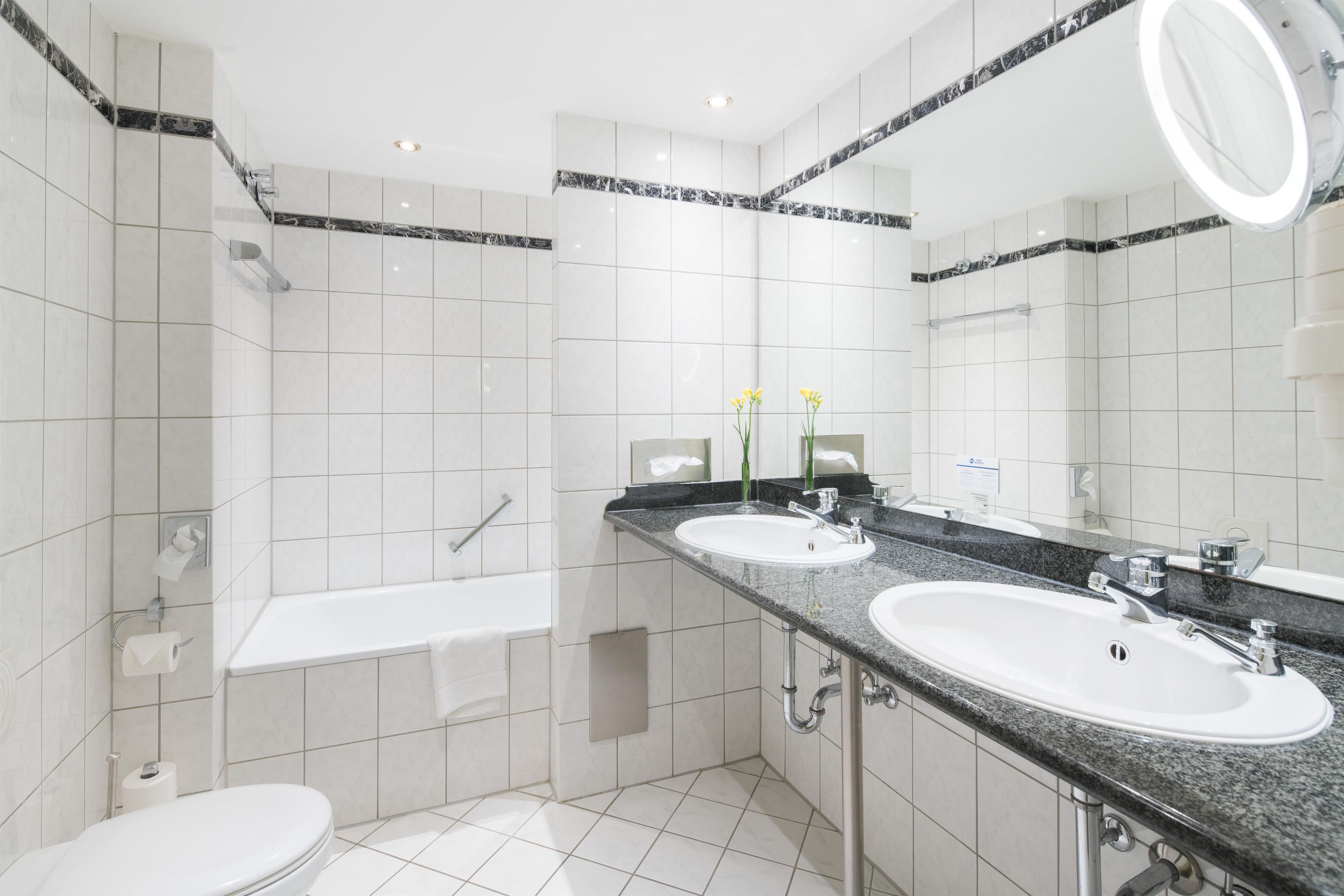 Un baño moderno con dos lavamanos, una bañera y un inodoro.