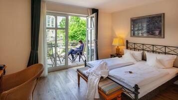 Habitación de hotel con cama, una silla, un banco, una mesa y vistas al exterior.
