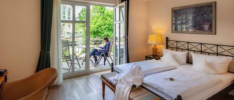Habitación de hotel con cama, una silla, un banco, una mesa y vistas al exterior.