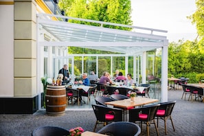An outdoor patio with tables and chairs, a glass enclosure, and a barrel. - Best Western Wein-Und Parkhotel Nierstein (Nierstein)