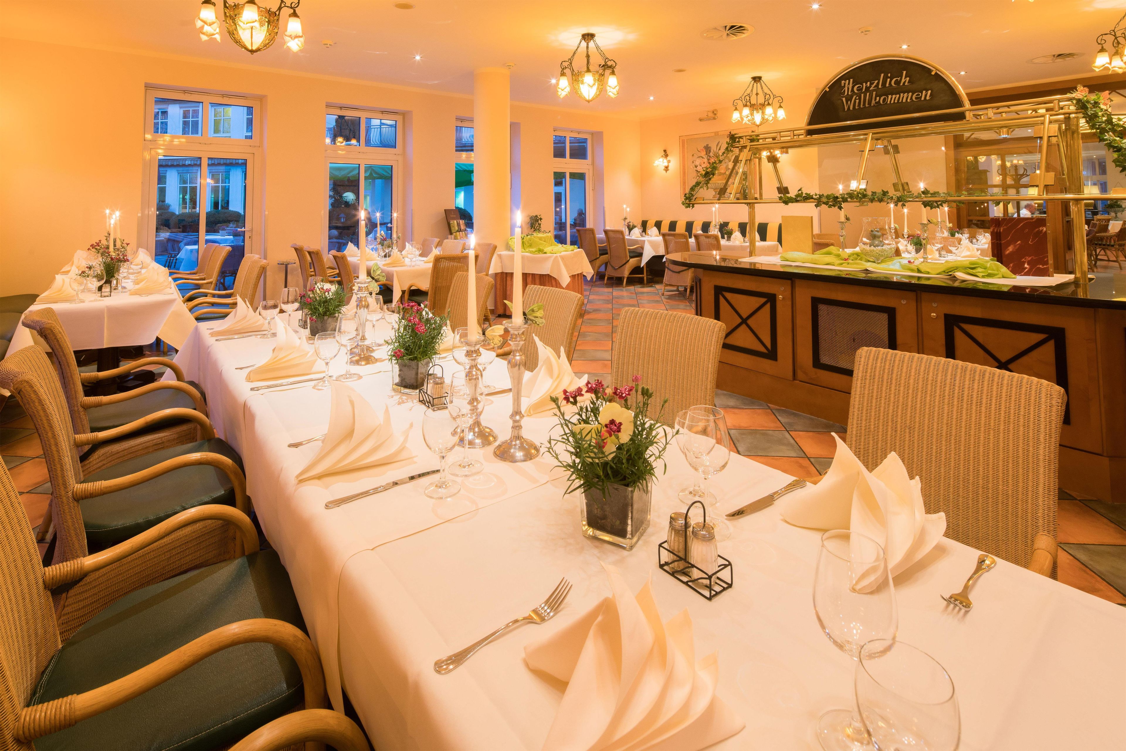 A restaurant with tables set for dining, featuring wicker chairs and white tablecloths.