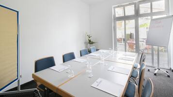 Een vergaderruimte met een lange tafel, stoelen en een whiteboard met tekst.