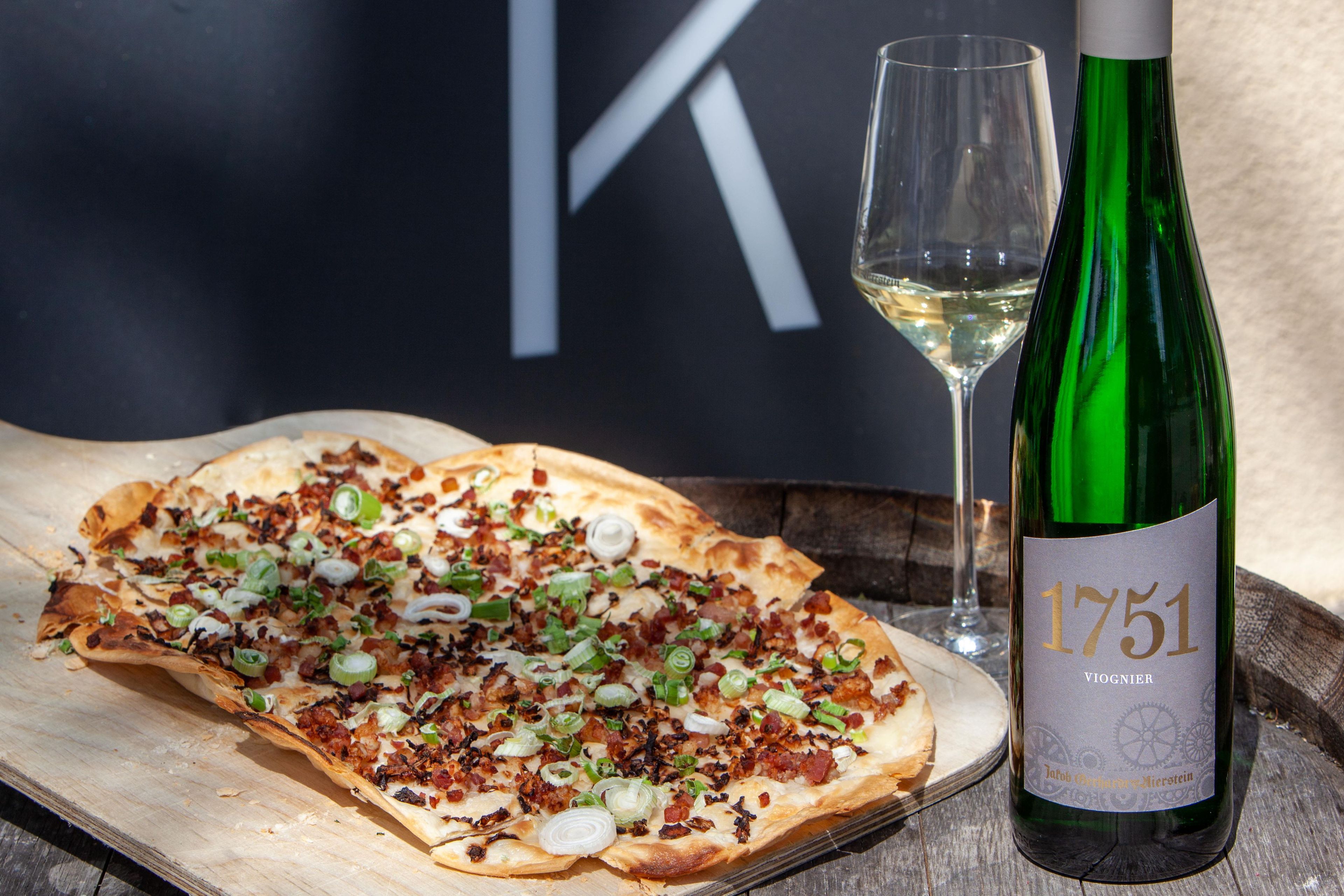 Una pizza sobre una tabla de madera, una botella de vino y una copa de vino.