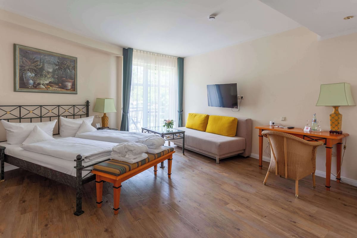 Ein Hotelzimmer mit Bett, Sofa, Fernseher und Tisch.