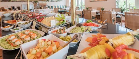 A buffet with various food options including fruits, vegetables, and cheeses.