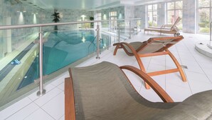 Un espace piscine avec des chaises longues et une rambarde en verre.