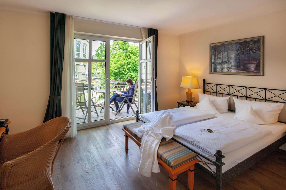 Ein Hotelzimmer mit Bett, Stuhl, Bank und Tisch, mit Blick nach draußen.