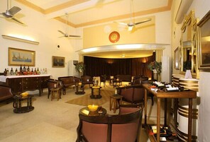 Un vestíbulo de hotel con zona de bar, disposición de asientos y un ventilador de techo.