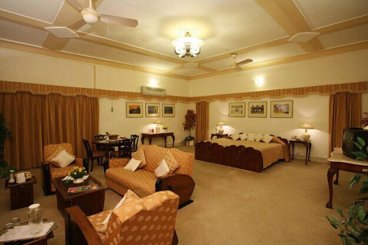 Habitación de hotel con sofá, sillón, mesa de comedor y televisor.