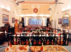Un comedor amplio con varias mesas y sillas, un ventilador de techo y un gran ventanal que proporciona luz natural.
