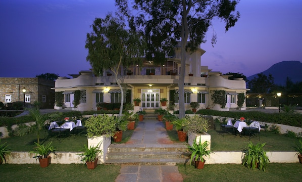 A hotel with a central entrance, potted plants, and outdoor seating. - Shikarbadi Hotel (Udaipur)