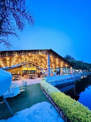 A building with a covered outdoor seating area, a pool, and a well-maintained lawn. - Shikarbadi Hotel (Udaipur)