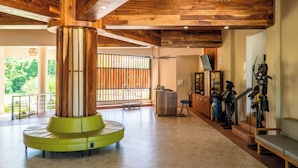 A lobby with a wooden ceiling, a green circular seating area, a reception desk, and a statue of a pirate. - Parador El Faro (Aguadilla)