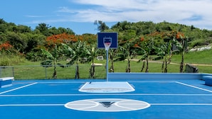 A basketball court with a blue surface and a sign that reads "SALTY BUM". - Parador El Faro (Aguadilla)
