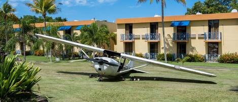A small airplane parked on a grassy area with a building in the background.