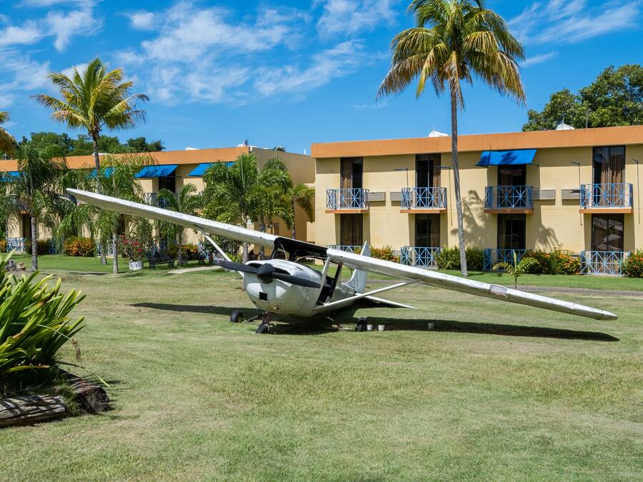 Un pequeño avión estacionado en un césped, con un edificio al fondo.
