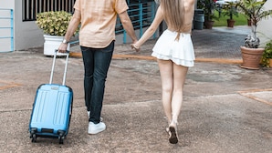 A couple holding hands, walking towards a building with a sign that reads "Hotel el FARO". - Parador El Faro (Aguadilla)