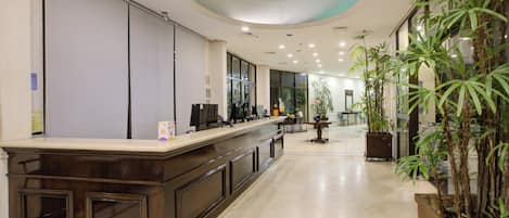 A reception area with a counter, seating, and potted plants.