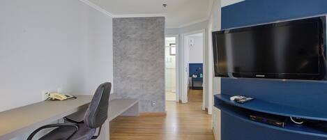 A modern office space with a desk, chair, and a mounted flat-screen TV.