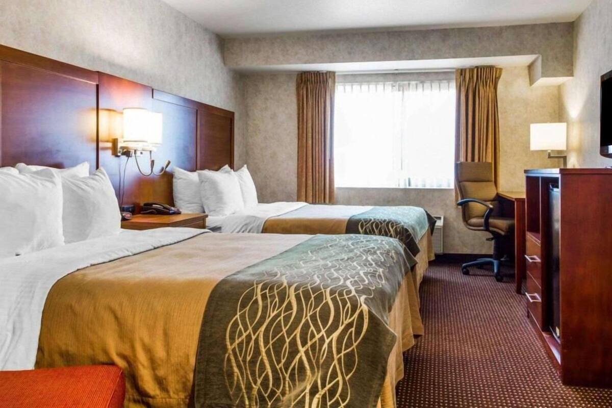 A hotel room with two beds, a desk, a chair, and a television.