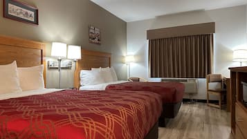 Una habitación de hotel con dos camas, un escritorio, una silla y un ventanal con cortinas.