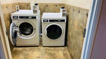 A compact laundry room with two front-loading washing machines and a small shelf with items on top.